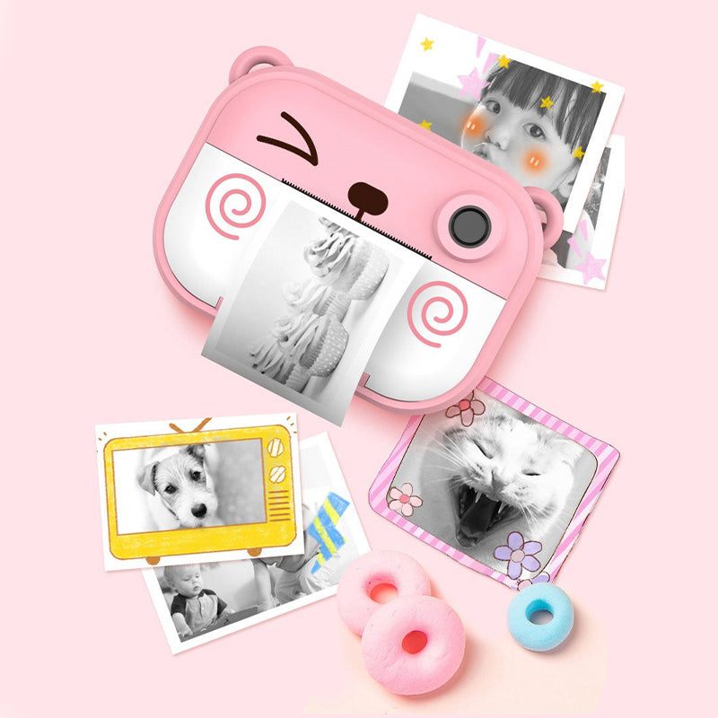 Pink kid instant print camera with black and white printed photos and decorative frames on a pink background